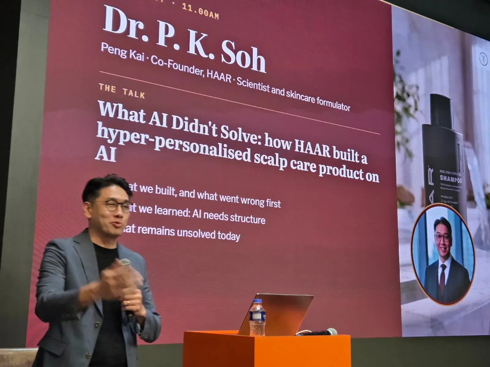 Dr. P. K. Soh gesturing as he speaks in front of a slide titled What AI Didn't Solve: how HAAR built a hyper-personalised scalp care product on AI.